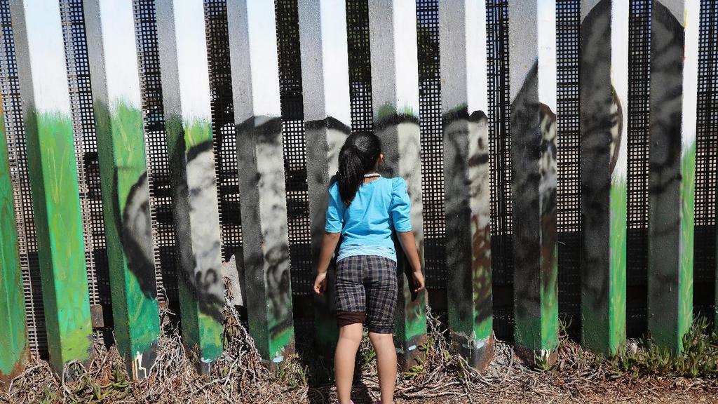 Una niña observa hacia California a través de la reja en la frontera con México. Crédito: John Moore/Getty Images
